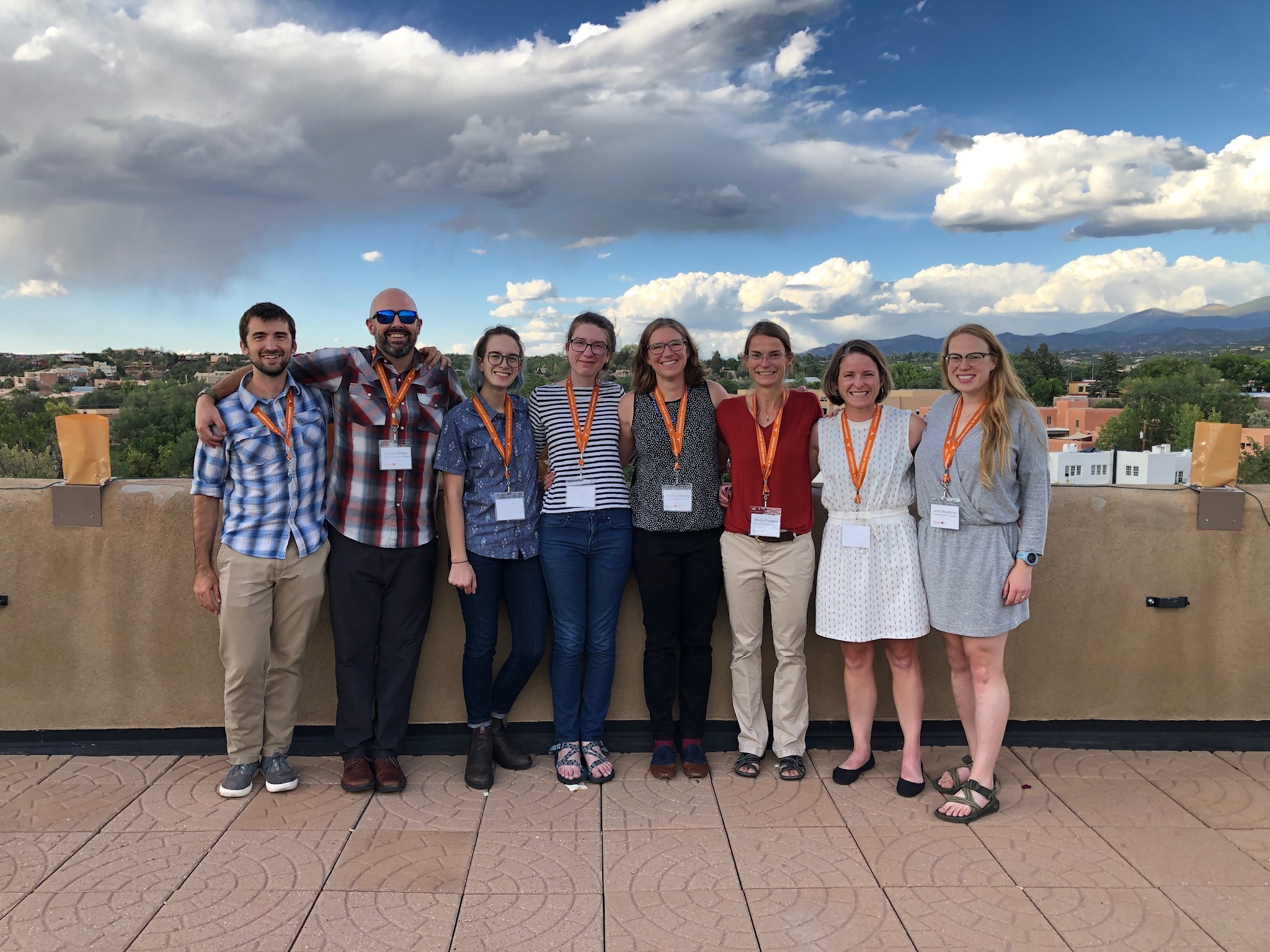 eight geologists standing on a rooftop patio with Santa Fe in the background