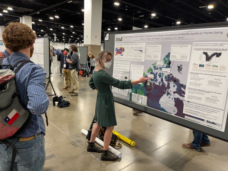 Scientist pointing to a research poster hanging on a billboard