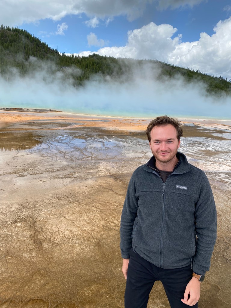 Liam standing in front of a hydrothermal lake in Yellowstone