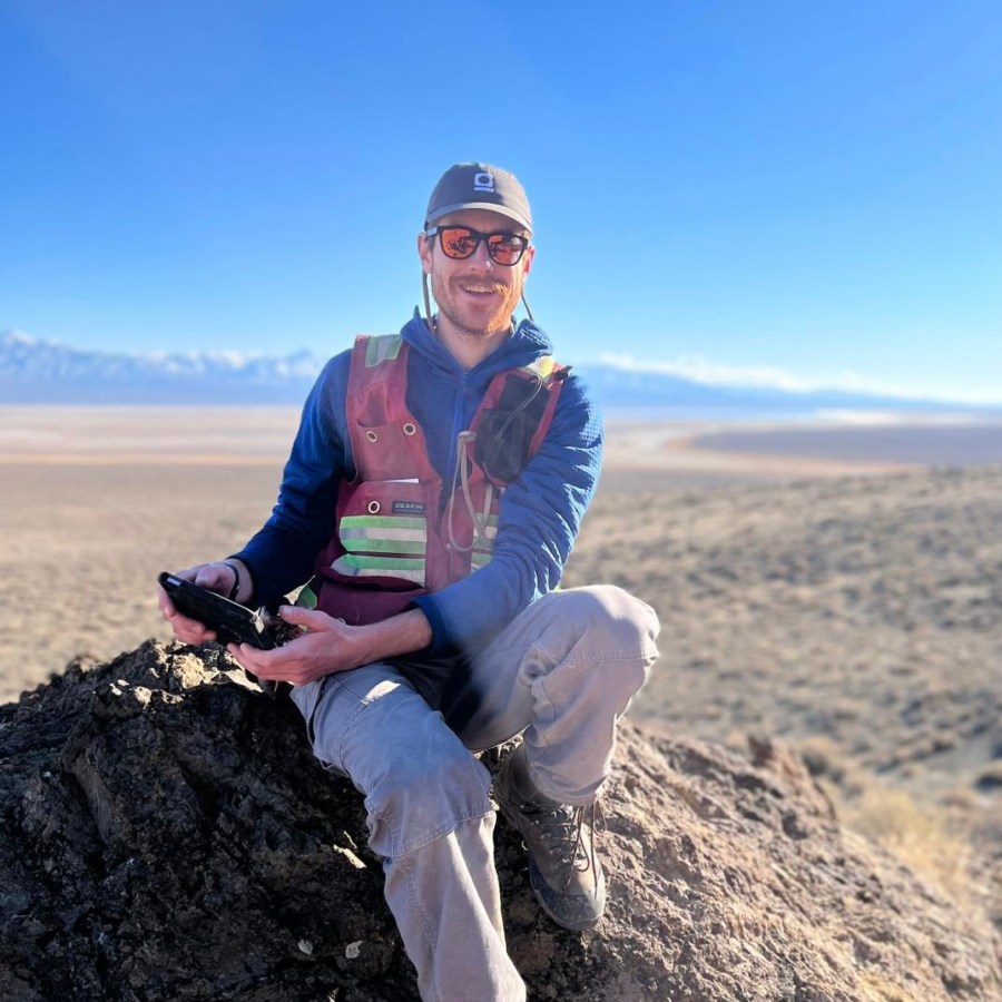 John sitting on a rock with mountains in the distance